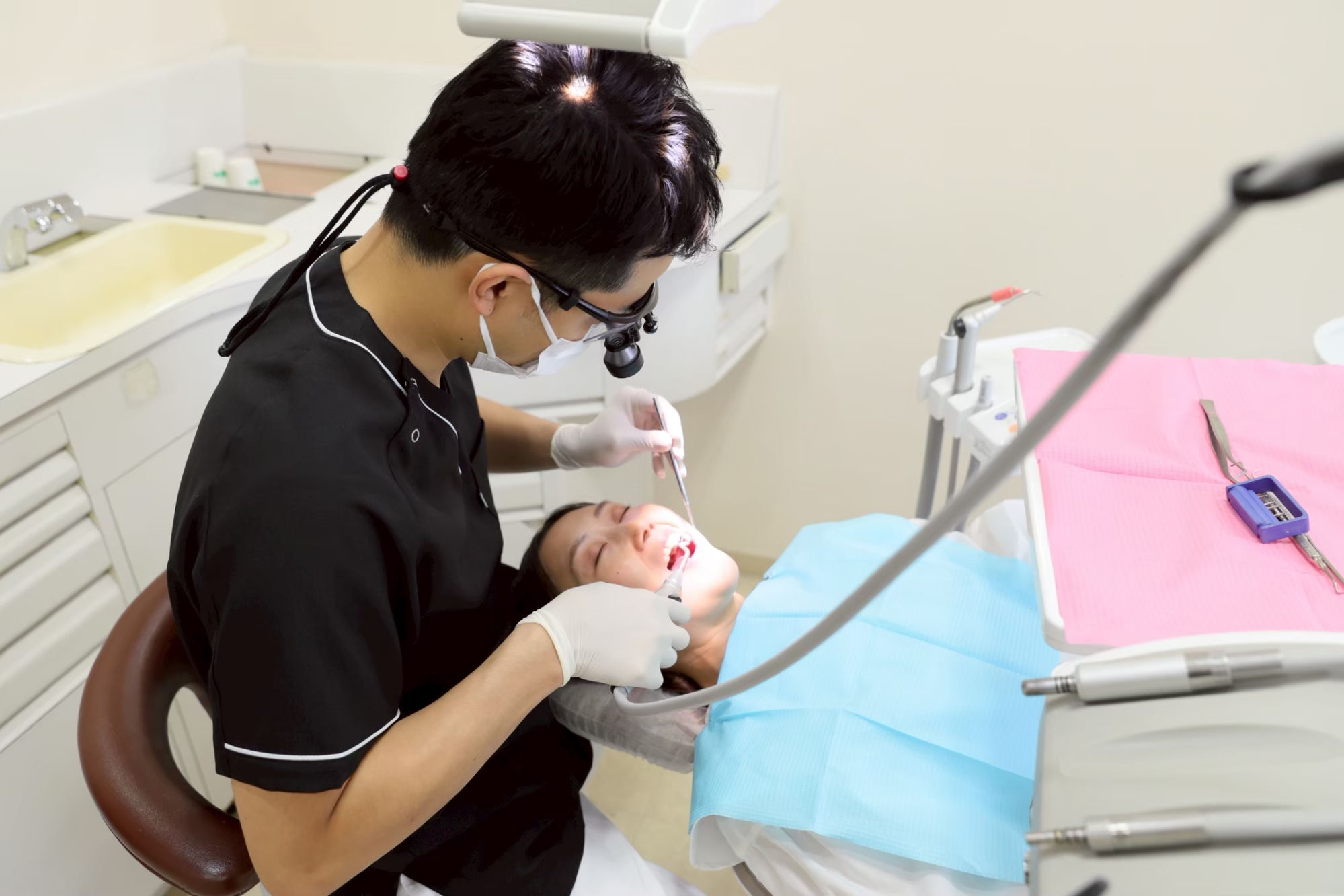 拡大鏡を使って丁寧に治療を行う歯科医師